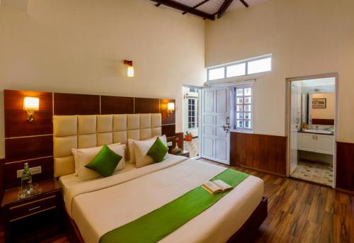 a bedroom with a large bed with green pillows at Rosewood by Nature Resorts and Stays in Ooty