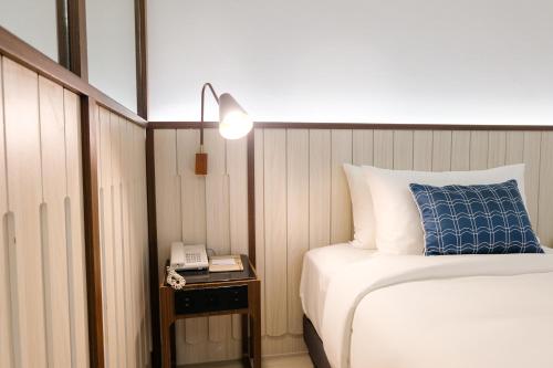 a bedroom with a bed and a phone on a table at Hotel Amber Sukhumvit 85 in Bangkok