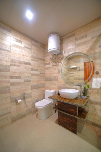 a bathroom with a toilet and a sink and a mirror at Yogved Hospitality & Resort in Rishīkesh