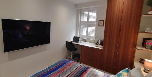 Schlafzimmer mit einem großen Flachbild-TV und einem Bett in der Unterkunft Comfortable Room With Ensuite in London