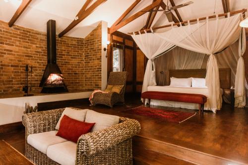 ein Schlafzimmer mit einem Bett, einem Sofa und Stühlen in der Unterkunft Elewana Arusha Coffee Lodge in Arusha