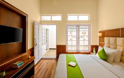 a bedroom with a large bed and a television at Rosewood by Nature Resorts and Stays in Ooty