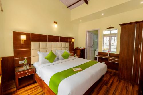 a large bedroom with a large white bed with green pillows at Rosewood by Nature Resorts and Stays in Ooty