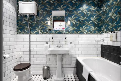 a bathroom with a toilet and a sink and a tub at Häringe Slott in Västerhaninge