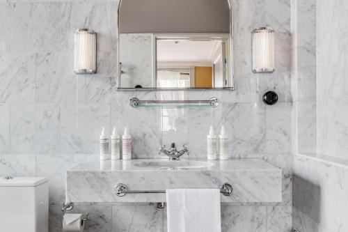 a white bathroom with a sink and a mirror at Häringe Slott in Västerhaninge