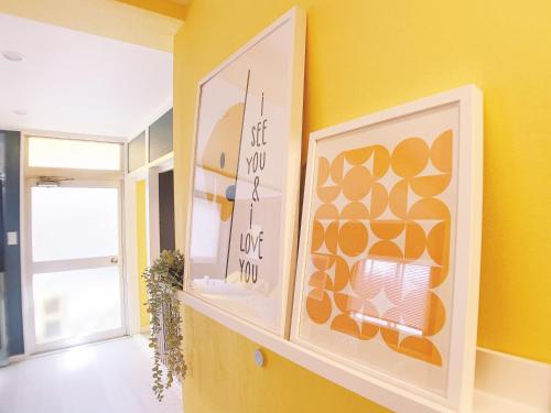 a yellow room with a shelf with two pictures on it at OUCHI HOTEL Nagarekawa with Dogs in Hiroshima