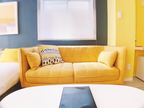 a living room with a yellow couch and a bed at OUCHI HOTEL Nagarekawa with Dogs in Hiroshima