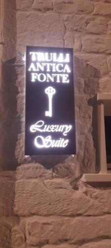 a neon sign hanging on a stone wall at Trulli Antica Fonte Luxury Suite in Alberobello