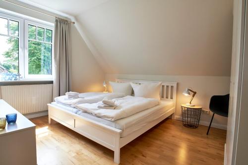 uma cama branca num quarto com uma janela em Heidehaus Wohnung 02 em Wyk auf Föhr