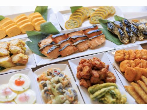 a table filled with different types of food on plates at Place Hotel Ascot in Kumamoto