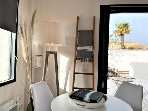 una mesa blanca con sillas y una lámpara en una habitación en Maisonnette à proximité plage et port de St-Martin, en Saint-Martin-de-Ré