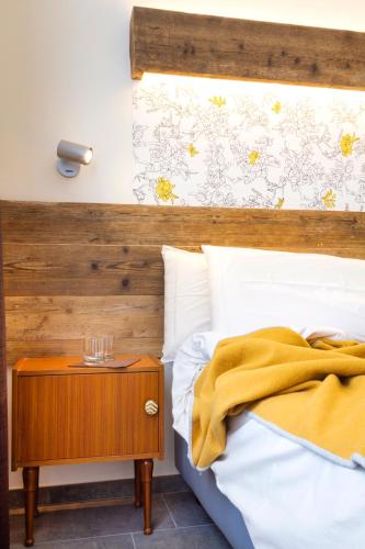 a bedroom with a bed with a wooden headboard and a nightstand at Hirondelle Locanda in Aosta