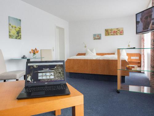 Zimmer mit einem Laptop auf einem Schreibtisch mit einem Bett in der Unterkunft Pension Huttental in Bad Soden-Salmünster