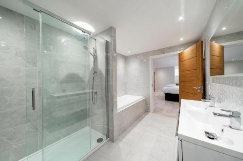 uma casa de banho com um chuveiro, um lavatório e uma banheira em W. Queen St. Apt. em Broughty Ferry