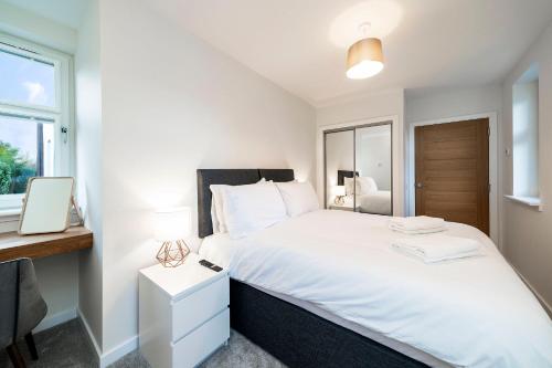 a bedroom with a white bed with a desk and a window at W. Queen St. Apt. in Broughty Ferry
