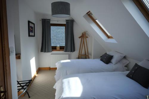 two beds in a room with a window at Hazelbank in Colbost