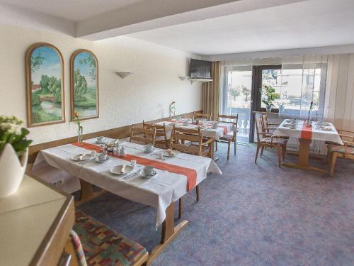 a dining room with tables and chairs and windows at Pension Huttental in Bad Soden-Salmünster