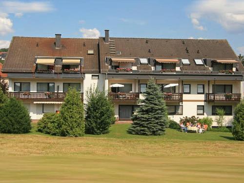 a large house with people sitting on a lawn in front of it at Pension Huttental in Bad Soden-Salmünster