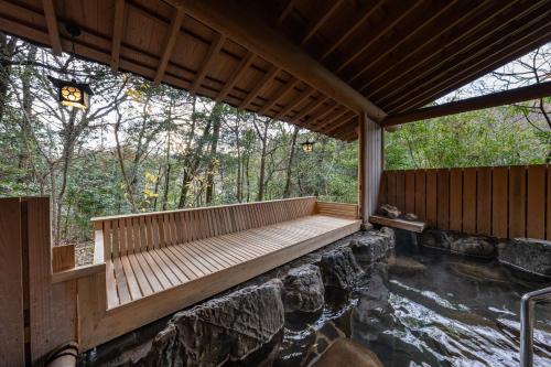 um deque de madeira junto a um rio na floresta em Ryokan Nushiya em Gotsu