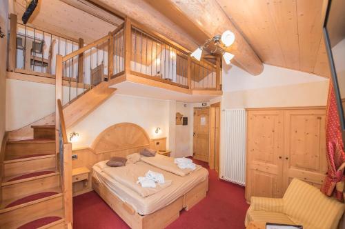 a bedroom with a large bed and a staircase at Hotel Capriolo in Livigno