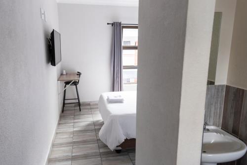 a bedroom with a bed and a sink and a bathroom at Ecomotel Isando in Kempton Park