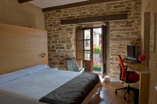 a bedroom with a bed, chair and a window at Posada Real de Las Misas in Puebla de Sanabria
