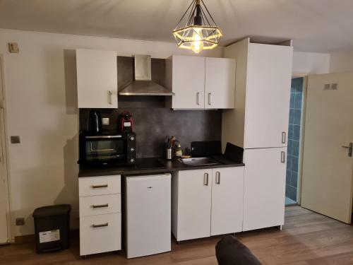 eine Küche mit weißen Schränken und einer Mikrowelle in der Unterkunft Studio proche de J. Jaurès et de l'hotel de ville in Saint-Étienne
