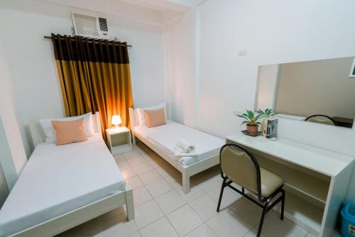 um quarto com 2 camas, uma secretária e uma cadeira em TARASA HOSTEL em Manila