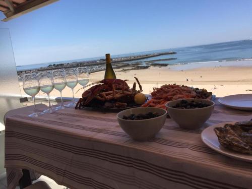 - une table avec des assiettes de nourriture et des verres à vin sur la plage dans l'établissement Superbe vue mer Pornichet, au 5e + parking couvert, à Pornichet