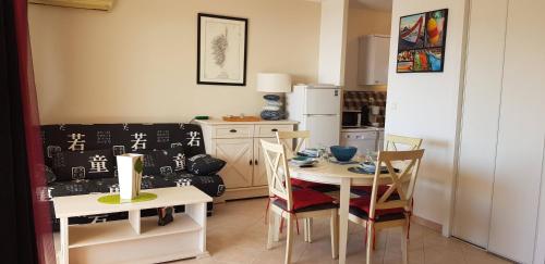 une cuisine avec une table, des chaises et un réfrigérateur dans l'établissement T1 vue mer bord de mer Ajaccio, à Ajaccio