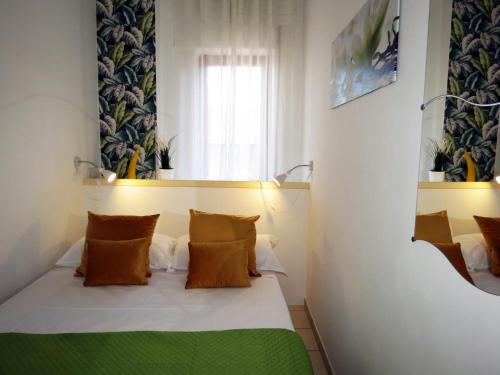 Habitación pequeña con cama con almohadas de color naranja en Syrene Apartment, en Sorrento