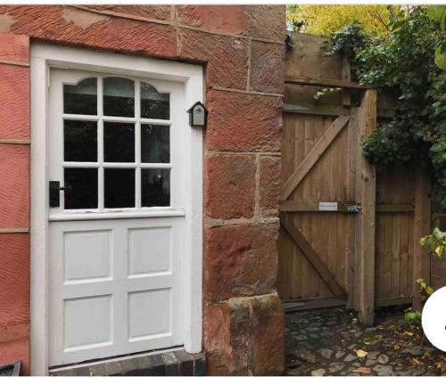 a white door and a wooden gate next to a brick building at Pear Tree Cottage Courtyard in Shrewsbury