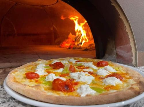 a pizza sitting on a plate in front of a pizza oven at Hotel Posidonia in Porto Cesareo