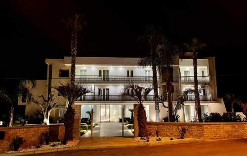 a large building with palm trees in front of it at Hotel Posidonia in Porto Cesareo