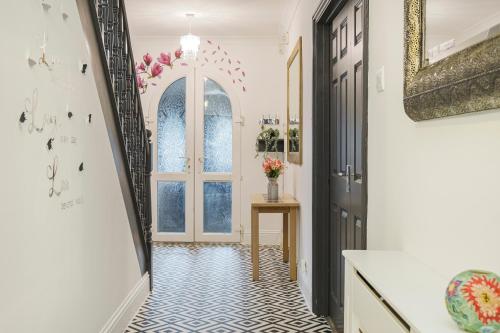 a hallway with a door and a table with flowers at Contractors, Larger Groups, sleeps 14, Iver House, Buckinghamshire, in Buckinghamshire