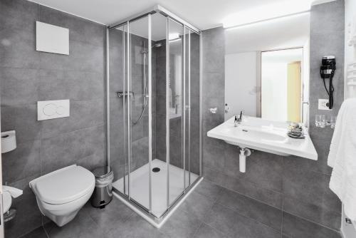 a bathroom with a shower and a toilet and a sink at Hotel Wasserfall in Jaun