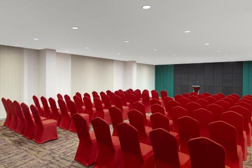 an empty conference room with red chairs and a podium at Elsotel Purwokerto By Daphna Management in Purwokerto