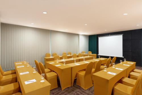 a conference room with yellow tables and chairs and a screen at Elsotel Purwokerto By Daphna Management in Purwokerto