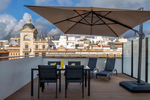 a table with chairs and an umbrella on a balcony at Tgna Rambla 68 in Tarragona
