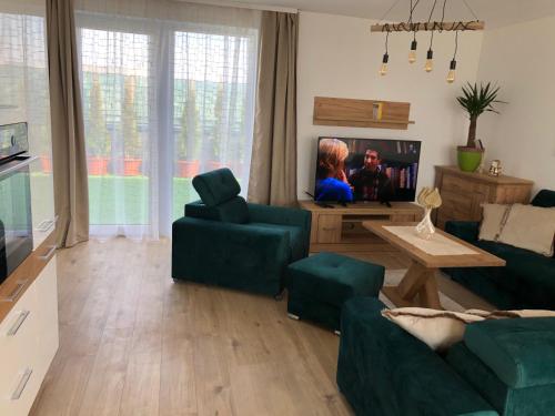 a living room with a couch and a tv at Tatra billetee apartmán s luxusným výhľadom na VysokéTatry a súkromným wellness in Poprad