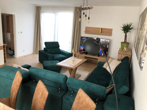 a living room with green couches and a tv at Tatra billetee apartmán s luxusným výhľadom na VysokéTatry a súkromným wellness in Poprad