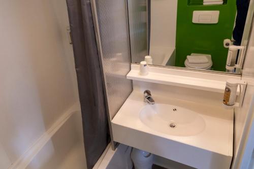 a bathroom with a sink and a mirror and a toilet at Hotel Victoria in Strasbourg