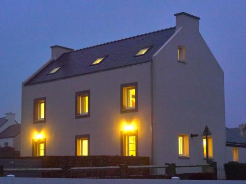 Casa blanca con ventanas iluminadas por la noche en l'Aod, maison d'hôtes insulaire en Lampaul