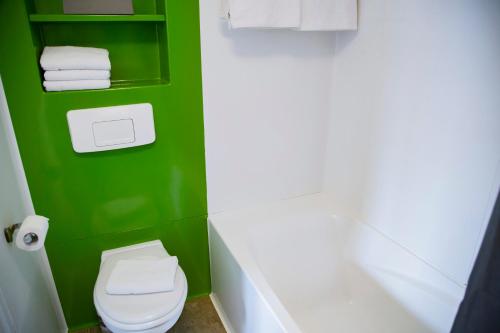 a green bathroom with a white toilet and towels at Hotel Victoria in Strasbourg