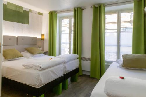 two beds in a room with green curtains at Hotel Victoria in Strasbourg