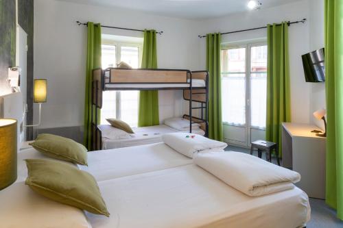 two bunk beds in a room with green curtains at Hotel Victoria in Strasbourg
