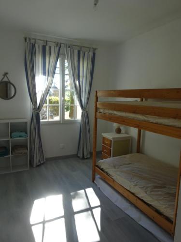 Un dormitorio con una litera y una ventana. en Rénovation proche lac et mer, en Landevieille