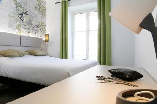 a hotel room with a bed and a table with a phone at Hotel Victoria in Strasbourg