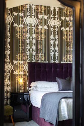 a bedroom with a bed with a purple headboard at Escape Boutique B&B in Llandudno