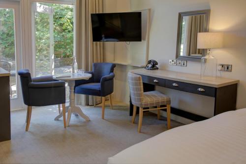 Habitación de hotel con escritorio, mesa y sillas en Lansdown Grove Hotel en Bath